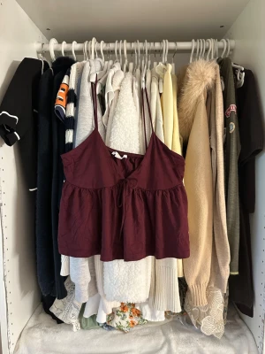 Vinrött linne från Gina Tricot - Säljer ett vinrött linne från Gina Tricot med tunna axelband och en söt knytning framtill. Linnet har en avslappnad passform och är tillverkat i mjuk bomull, perfekt för varma dagar eller som layering-plagg.