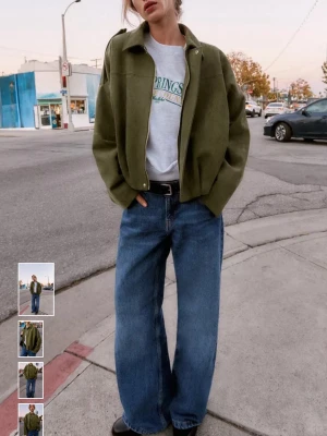 Olivgrön oversized mockajacka - Snygg olivgrön mockajacka i oversized passform med klassisk krage och guld dragkedja framtill. Jackan har långa ärmar och en minimalistisk look som passar perfekt till jeans. Materialet ger en lyxig känsla och jackan har en avslappnad siluett.