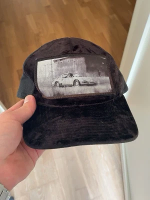 Svart keps med biltryck - Säljer min keps med biltryck från Hatstore. Bortsett från att flera av knapparna där bak har gått av så är kepsen i fint skick, perfekt för sommaren. Pris kan diskuteras!!