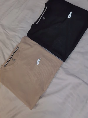 Nike t-shirts i svart och beige - Två stilrena t-shirts från Nike, en i svart och en i beige. Båda har klassisk passform, rund halsringning och den ikoniska Nike-loggan broderad på bröstet. Perfekta för en clean och sportig look. Helt nya passar smal kan passa medium sitter lite mer tight men funkar 350 st eller 600 för båda 