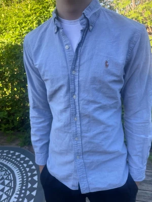 Ljusblå skjorta från Ralph Lauren - Raffe skjorta! Storlek M! Personen på bilden är 184 cm väger 70 kg! Modellen passar 180-187 cm! Hör av er vid funderingar!