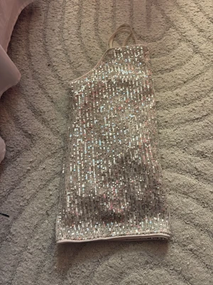 Glittrig silver paljettopp från Kappahl  - Säljer en glittrig topp i silver med tunna axelband och massor av paljetter. Toppen har en rak passform och är perfekt för dig som vill sticka ut. Materialet känns mjukt och stretchigt, och toppen är ärmlös med en snygg oneshoulder-look. Har aldrig använt, men köpte den för några år sen 💓 pris kan diskuteras ❤️