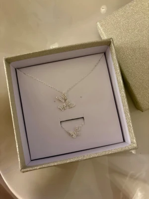Silverfärgat smyckeset med fjärilar - Set med halsband och armband i silverfärg, båda med detaljerade fjärilar dekorerade med glittriga stenar. Matchande med fjärilar, glittriga stenar och båda är i 925. Levereras i en glittrig presentask💗 Använd gärna KÖP NU💕