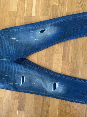 Blå slitna jeans med hål, repay - Säljer ett par blå jeans med slitningar för en riktigt trendig och avslappnad look. Jeansen har smal passform och klassiska bakfickor. Perfekta för dig som gillar streetstyle och vill sticka ut.
