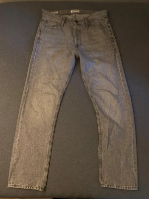 Grå raka jeans  - Säljer ett par gråa jeans från Jack n jones med rak passform och klassisk femficksdesign. Jeansen har normal midja och är tillverkade i ett slitstarkt denimtyg. Perfekta för dig som gillar en clean och enkel stil.