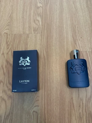 Parfums de Marly Layton 125 ml - Parfums de Marly Layton är en lyxig parfym i en matt mörkblå flaska med silverfärgad kork. Flaskan rymmer 125 ml och har märkets ikoniska logga ingraverad. Kommer med originalkartong i matchande färg och elegant design. Har knappt använt den har bara sprejat 1-4 gånger 