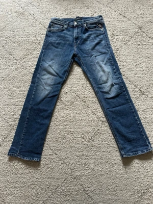 Blå jeans från Replay model thad - Säljer ett par klassiska blå jeans från Replay med raka ben och snygga slitningar vid knäna. Jeansen har fem fickor, knappgylf och är tillverkade i bomull med lite stretch för extra komfort. Perfekta för en avslappnad och trendig look. Storlek 150cm/12 A