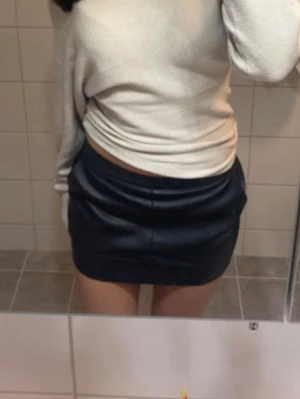 Svart skinnkjol med dragkedja - Säljer en svart kort skinnkjol med snygg dragkedja bak. Kjolen har en tight passform. Perfekt att matcha med en stickad tröja eller crop top. 