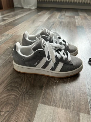 Grå Adidas Campus sneakers - Ett par Adidas Campus 00s i grå mocka, dom är i storlek 38✨ Skorna är i fint skick och sparsamt använda. Inga större märken eller slitage, sulorna är fräscha. Extra grå skosnören medföljer 