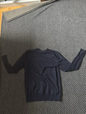 Mörkblå enkel långärmad tröja - En stilren mörkblå långärmad tröja med rund hals och ribbade muddar vid ärmslut och nederkant. Perfekt för dig som gillar minimalistisk design och vill ha något som funkar till många olika outfits.