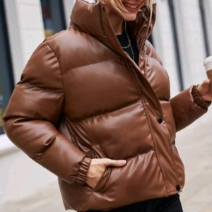 HELT NY OCH OANVÄND snygg brun höst / vinterjacka. Strlk: Small, 36 - HELT NY OCH OANVÄND snygg brun höst/vinterjacka i läderimmitation. Strlk: Small, 36. Polyuretan, polyester/vadderad. Har dragkedja, knappar, fickor. INGA defekter. Varm och skön. 