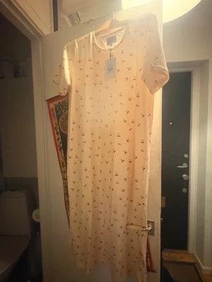 LIBERTE DAM KLÄNNING ALMA 9562. - YELLOW CHERRY stl M/L  - LIBERTE DAM KLÄNNING ALMA 9562. - YELLOW CHERRY. Långklänning med körsbärsmönster. Är cirka 122 cm lång. Klänningen har korta ärmar och en rund halsringning. Den är designad i en t-shirtmodell och når ungefär till anklarna. Jag fick den i en mysteriebag från MollyandMy men säljer då den inte är min still. Hämtas på Södermalm i Stockholm eller skickas till dig. Du bestämmer. Maila mig vid frågor.  Med vänlig hälsning, Fanny. 