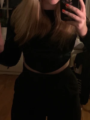 Svart  topp - Snygg svart croppad topp från NA-KD i mjuk sammet. Modellen har långa ärmar och en enkel, stilren design som passar perfekt till byxor eller kjol. Perfekt för dig som gillar trendiga och bekväma plagg med lite edge. Den är i samets. Så den blir lite ”lyxigare” än bara en vanlig bomullstopp. Tyckte iallafall jag när jag köpte den. Pris går alltid att diskutera<3