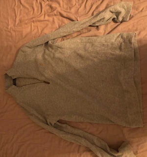 Grå halvzip tröja från Ralph lauren - Snygg grå långärmad tröja från Gant med halv dragkedja vid halsen. Tillverkad i mjukt material och har en Ralph lauren logga på bröstet. Perfekt för lager på lager och enkel att matcha med jeans eller chinos.