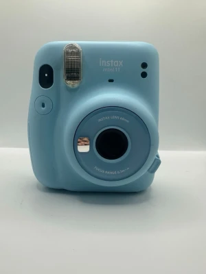 Blå Fujifilm Instax Mini 11 kamera - Säljer en ljusblå Fujifilm Instax Mini 11 direktfilmskamera. Kameran har rundade former, inbyggd blixt och en 60mm lins. Tillverkad i plast och perfekt för att ta instant-bilder. Enkel att använda och smidig att ta med sig.