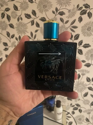 Versace Eros Eau de Toilette 100ml - Versace Eros Eau de Toilette i en lyxig, mörkblå glasflaska med gulddetaljer och Medusa-huvud på framsidan. Flaskan har en fyrkantig form och blått lock med guldkant. Kommer med originalkartong i matchande blå färg.