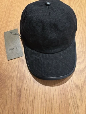 Svart keps från Gucci - Snygg svart keps från Gucci. Justerbar, perfekt accessoar för dig som gillar lyxiga detaljer och streetstyle.