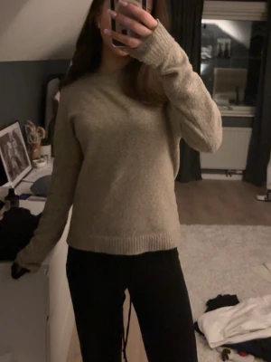 Beige stickad tröja med rund hals - Mysig beige stickad tröja med rund hals och långa ärmar. Tröjan har ribbade muddar vid ärmslut och nederkant. Perfekt att matcha med jeans eller leggings för en avslappnad stil.