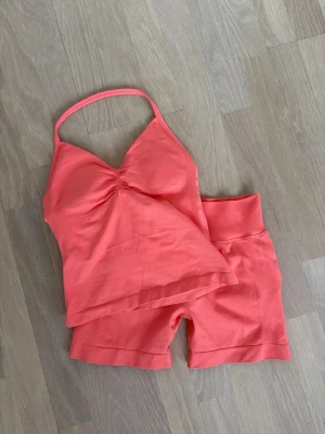 Korallfärgat underklädesset GTECH - Säljer ett korallfärgat träningsset från GTECH med ett linne med smala axelband och lätt rynkning vid bysten samt matchande shorts med bred resår i midjan. Setet är tillverkat i ett mjukt och stretchigt material som sitter skönt mot kroppen. UNDER DELEN I STORLEK M. ÖVERDEL STORLEK  S. Pris kan diskuteras 