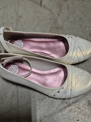 Ballerinaskor - Säljer ett par beige ballerinaskor från Marmelata med dekorativa sömmar och små silverfärgade nitar på tån. Skorna har en rundad tå och ljusrosa innersula som ger en snygg kontrast. Perfekt för dig som gillar stilrena och klassiska detaljer.