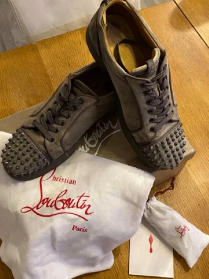 Christian Louboutin grå sneakers - Tja Säljer ett par gråa Christian Louboutin med klassiska nitar på sulan.Jag säljer dom för att jag har växt ut dom allt og följer med. Mitt pris är 1599 eftersom att de är i bra skick tar even byte 😁Storlek 42. skriv om funderingar.  