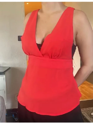 Röd mesh omlottopp med snörning bak - Snygg röd mesh omlottopp med djup v-ringning och breda axelband. Toppen har en unik snörningsdetalj i ryggen som ger en cool look och justerbar passform. Perfekt att styla med jeans eller kjol för en trendig outfit.