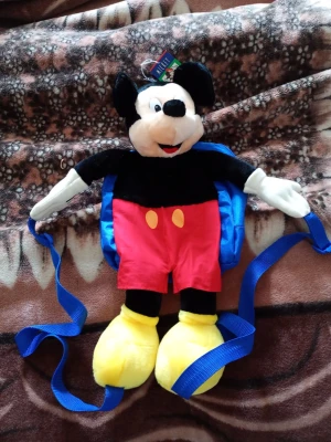 Musse Pigg ryggsäck i plysch - Söt ryggsäck formad som Musse Pigg med mjuk plyschdesign. Framsidan har Musse Piggs ansikte och kropp med röda byxor och gula skor, medan baksidan är blå med texten 'MICKEY'S BACK!'. Justerbara axelband och dragkedja. Perfekt för dig som gillar Disney. För barn alternativ samlar grej.