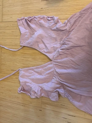 Ljusrosa topp - Supersöt ljusrosa topp från lager 157 med volangdetaljer vid axlarna och tunna axelband. Toppen har en lätt rynkad midja och är tillverkad i ett mjukt, strukturerat tyg som känns skönt mot huden. Perfekt för varma dagar och somriga vibes.