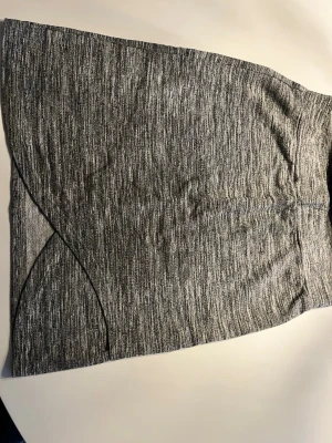 Gråmelerad kortkjol i bomull - Snygg gråmelerad kortkjol med enkel och stilren design. Kjolen har en lätt A-linjeform och är tillverkad i mjukt bomullsmaterial som ger en bekväm passform. Perfekt att matcha med en t-shirt eller hoodie för en avslappnad look.