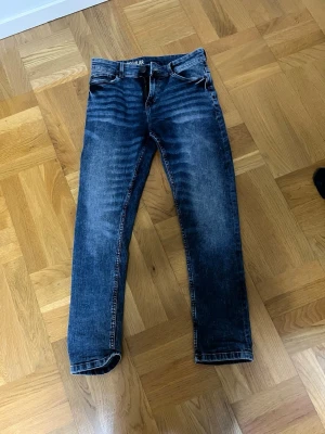 Blå raka jeans från Regular passar 12y - Säljer ett par klassiska blå jeans från Regular med raka ben och femficksmodell. Jeansen har en snygg tvättad look med ljusare partier och slitningar framtill. Perfekta till en avslappnad stil och passar till det mesta i garderoben. Str 12y