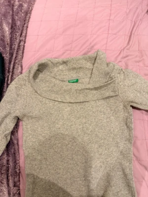 Ljusgrå stickad tröja Benetton - Säljer en ljusgrå stickad tröja från Benetton med bred, nedvikt krage och långa ärmar. Tröjan har en enkel och stilren design som passar perfekt till många olika outfits. Mjuk och skön kvalitet.