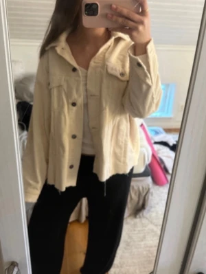 Beige oversized jeansjacka - Snygg beige jeansjacka i oversized modell med klassisk krage och bröstfickor med lock. Jackan har knappar framtill och rå kant nedtill för en trendig look. Perfekt att slänga över en t-shirt för en avslappnad stil.