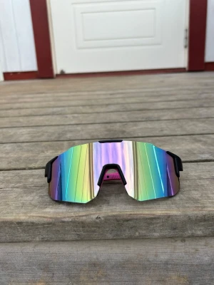 Rosa pastell Sportsolglasögon med svart ram - Säljer ett par sportiga solglasögon med glas i pastellfärger och svart båge. One size för vuxna och unisex. Fler bilder kan skickas vid seriöst intresse. 