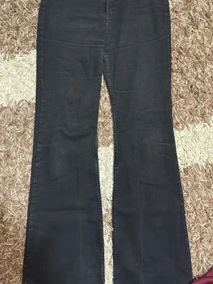Svarta bootcut jeans från Vila - Säljer ett par svarta bootcut jeans från Vila med hög midja och klassisk femficksdesign. Jeansen har vida ben och är tillverkade i ett mjukt denimtyg som ger en snygg siluett. Perfekta för dig som gillar en retroinspirerad look.