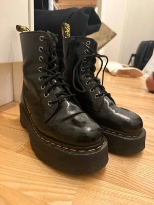 Svarta Dr. Martens med platå - Säljer ett par svarta Dr. Martens stövletter i skinn med höga platåsulor och klassiska gula sömmar. Sparsamt använda.