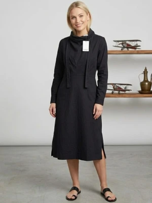 Svart långärmad klänning Rodebjer - Stilren svart långklänning från Rodebjer med långa ärmar och hög krage med knytband. Klänningen har slitsar nedtill på båda sidor och en rak, elegant siluett. Perfekt för dig som gillar minimalistisk design och tidlösa plagg. Helt ny. 