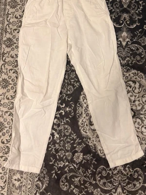  linnebyxor H&M - Säljer ett par vita linnebyxor med rak passform och avslappnad look. Byxorna har elastisk midja och är tillverkade i ett lätt och luftigt linnetyg, perfekta för en chill och stilren outfit. Inga synliga detaljer eller loggor.