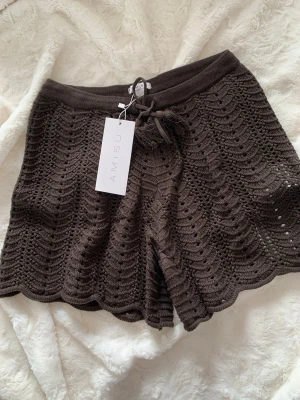Bruna virkade shorts från Amisu - Snygga bruna virkade shorts från Amisu med vågig kant och snörning i midjan. De har ett unikt mönster och är perfekta för varma dagar. Materialet är stickat och ger en avslappnad vibe.