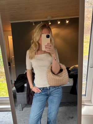 Beige flätad handväska  - Säljer en superfin beige handväska rundad form, kort handtag och dragkedja upptill. Tillverkad i mjukt läder som känns 