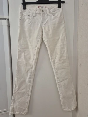 Jeansbyxor - Snygga vita jeans från Ichi och klassisk femficksmodell. Jeansen har bälteshällor, silverfärgade nitar och dekorativa sömmar på bakfickorna. Tillverkade i ett mjukt bomullsmaterial som är bekvämt att bära. 28 tum. Har fläckar.