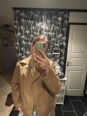 Beige/brun skinnjacka  - Snygg beige skinnjacka från Pieces med silvriga dragkedjor och knappar. Jackan har även ett skärp till midjan. Som ny!! 