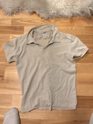 Beige pikétröja från Kappahl - Klassisk beige pikétröja från Kappahl med korta ärmar och mjuk krage. Tillverkad i bomull. Dock så är min lille brors namn inskrivet i tyget så kan förhandla 
