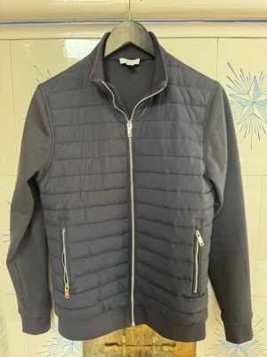 Reiss  cardiganjacka - En Stilren mörkgrå cardiganjacka från Riess med quiltad framsida och släta ärmar. Jackan har hel dragkedja, ståkrage och två fickor med dragkedja framtill och Nästintill Helt oanvänd!    Perfekt till Våren och Sommaren!  Passar S-M fint också. Skriv privat för bilder eller funderingar!