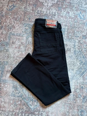 Svarta jeans från Diesel - Snygga svarta jeans från Diesel med klassisk femficksmodell och bootcut. Jeansen har en tydlig Diesel-lapp bak i midjan och är tillverkade i ett mjukt, stretchigt material som sitter skönt. Perfekta för dig som gillar en clean och stilren look.