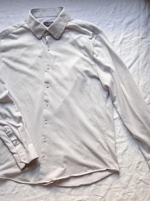 Ljusgrå skjorta med knappar - Säljer en stilren ljusgrå skjorta från Selected Homme. Skjortan har klassisk krage, långa ärmar och knäppning framtill. Tillverkad i mjuk bomull och passar perfekt till både jeans och chinos. Enkel och clean look!