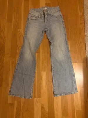 Ljusblå bootcut jeans - Säljer ett par ljusblå bootcut jeans med klassisk femficksdesign och mid waist. Jeansen har en avslappnad passform och är tillverkade i denim. Perfekta för en trendig och avslappnad stil.
