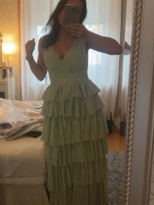 Mintgrön långklänning - Bubbleroom - Helt ny, endast testad 1 gång. Supersnygg mintgrön långklänning från Bubbleroom med flera lager volanger och v-ringad både fram och bak. 