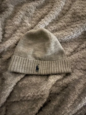 Ralph Lauren mössa - En stilig grå mössa från Ralph lauren, perfekt för våren eftersom den inte är för varm. Passar till mycket och har en väldigt bra pass form. Hör gärna av dig vid frågor