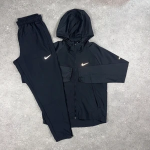 Nike Miller Tracksuit - Svart - Nike Miller Tracksuit - Svart •  Jacka och byxa i matchande färg • Storlekar från XS till 2XL • Går också att få på activez,se