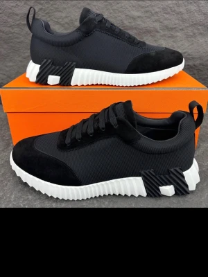 H märkes skor - Stilrena svarta sneakers med vit, räfflad sula och detaljer i mocka och mesh. Skorna har svarta skosnören, dragflik bak och coola geometriska detaljer på sidan av sulan. Perfekta för dig som gillar en modern och sportig look.